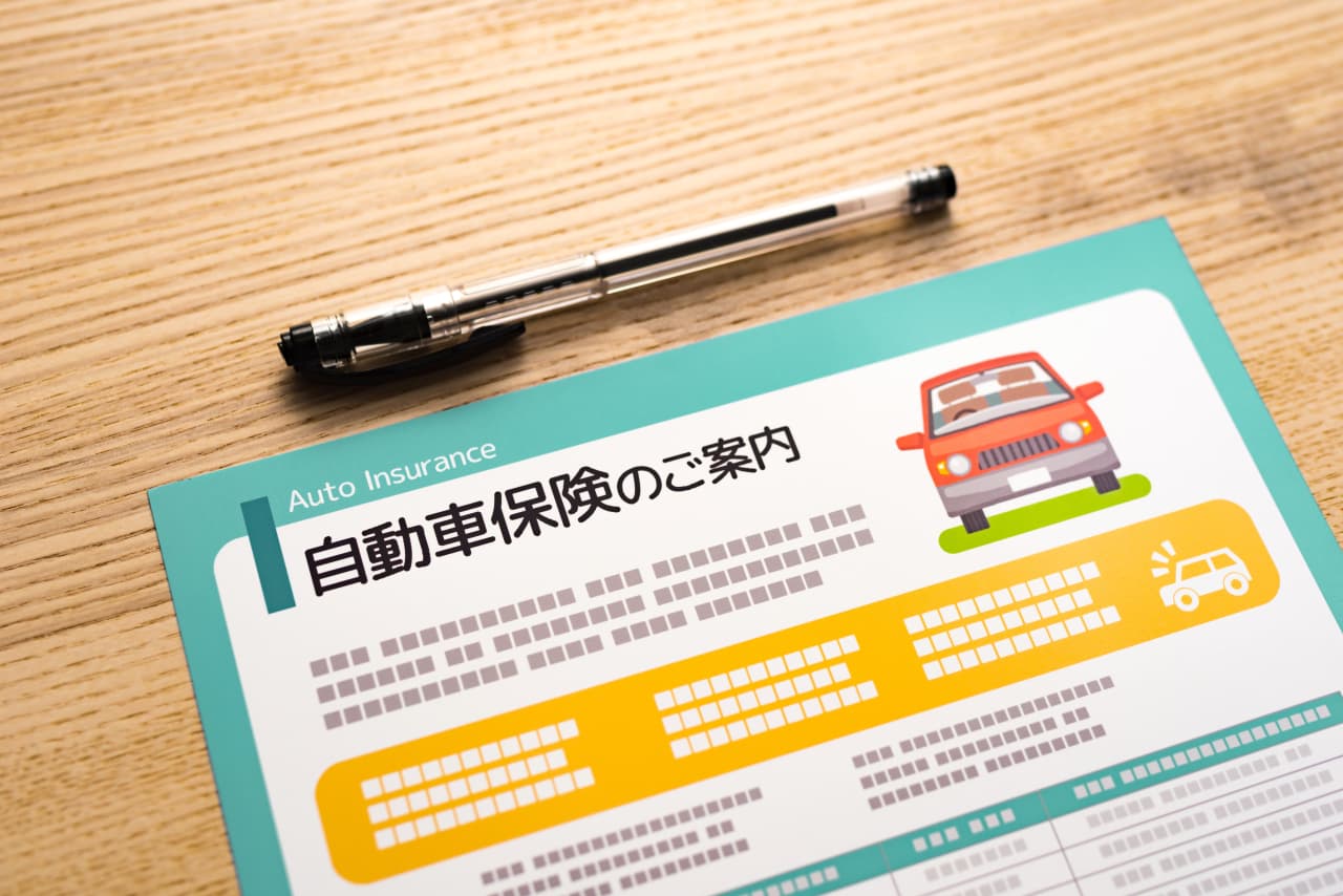 机の上に置かれた自動車保険のご案内とペン