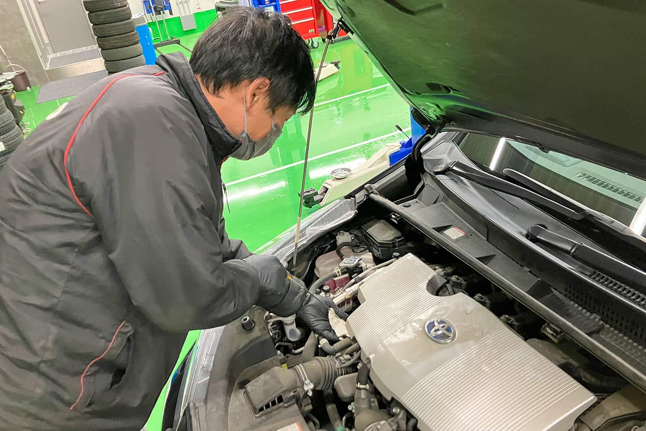 エンジンルームの細部を丁寧に点検する整備士。