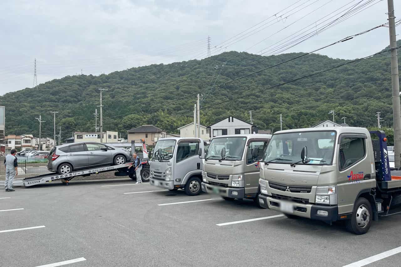 積載車による車両積み込み作業と、並列するキャリアカーの列