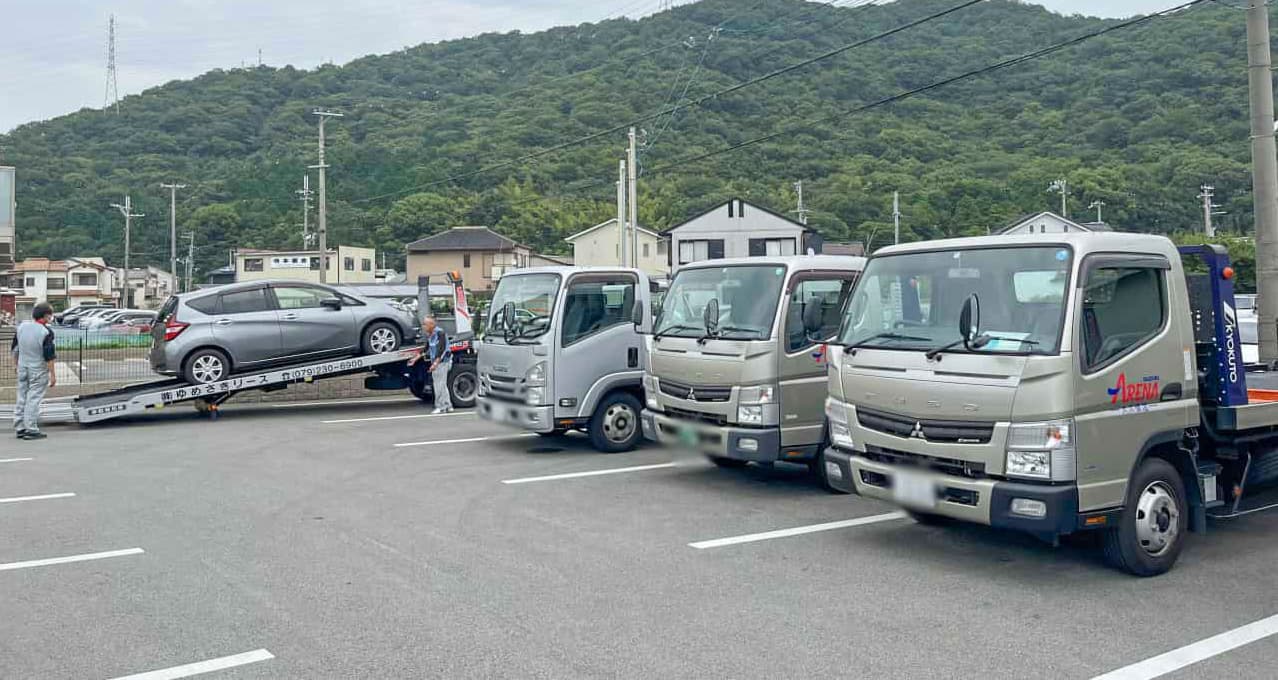 積載車による車両積み込み作業と、並列するキャリアカーの列